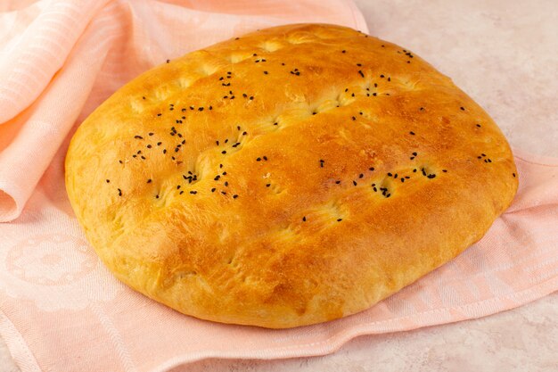 Foto gratuita una vista frontal pan horneado caliente sabroso envuelto en una toalla rosa sobre fondo rosa desayuno de masa de panadería