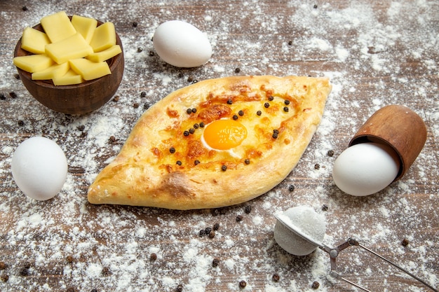 Vista frontal de pan de huevo horneado con harina en la superficie marrón desayuno de pan de huevo de masa de bollo