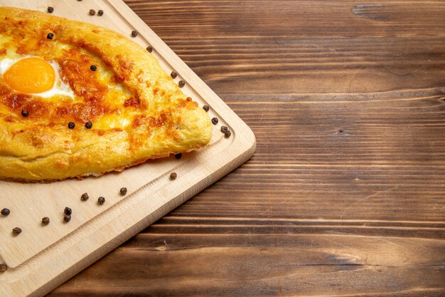 Vista frontal de pan recién horneado con huevo cocido en la superficie rústica marrón comida desayuno hornear bollo comida