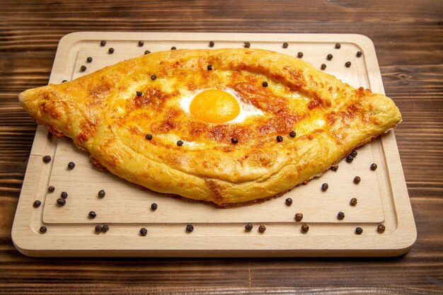 Vista frontal de pan recién horneado con huevo cocido en la superficie rústica marrón comida desayuno huevo bollo comida