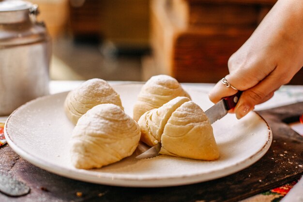 Una vista frontal de la panadería oriental de Badambura con nueces dulces en el interior en rodajas dentro de la placa blanca masa de masa para galletas