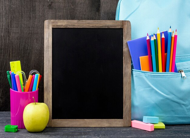 Vista frontal de papelería de regreso a la escuela con lápices de colores y pizarra