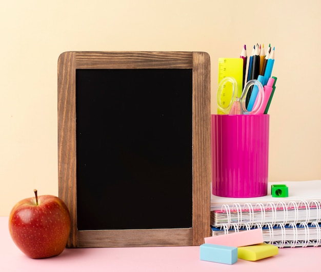 Vista frontal de papelería de regreso a la escuela con manzana y pizarra