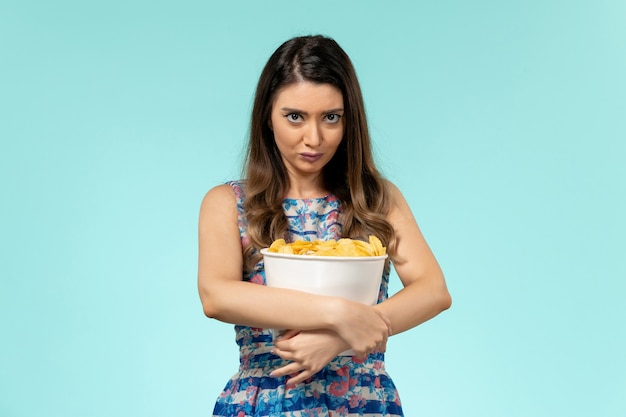 Vista frontal del paquete de explotación femenina joven con chips en el escritorio azul