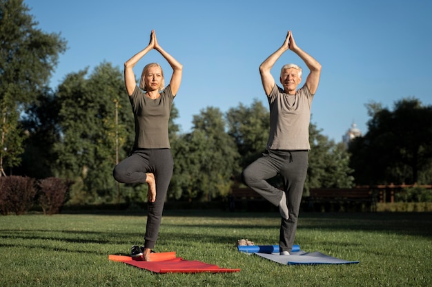 Vista frontal de la pareja de ancianos haciendo yoga al aire libre