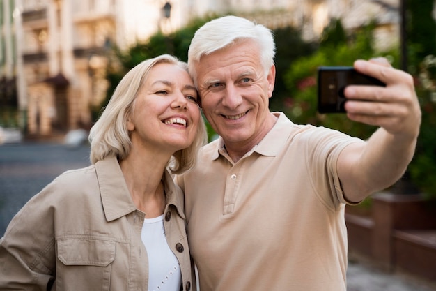 Vista frontal de la pareja de ancianos tomando un selfie mientras está en la ciudad
