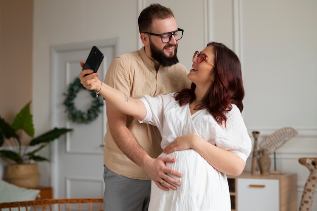Vista frontal pareja anunciando embarazo con teléfono inteligente