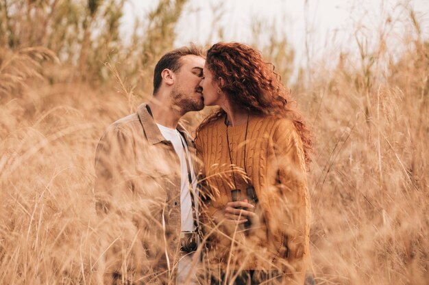 Vista frontal pareja besándose en el campo de trigo