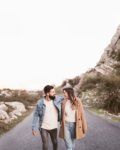 Vista frontal pareja caminando por una carretera