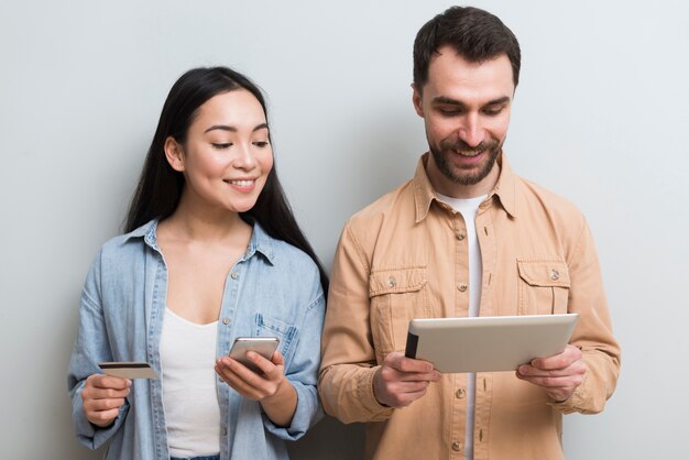 Vista frontal de una pareja comprando en línea en diferentes dispositivos