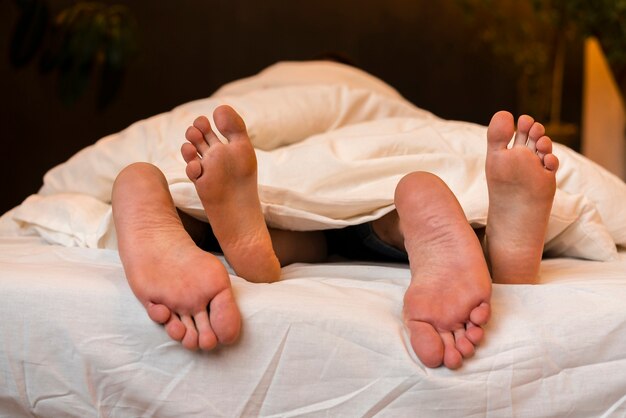 Vista frontal de la pareja descalza en la cama