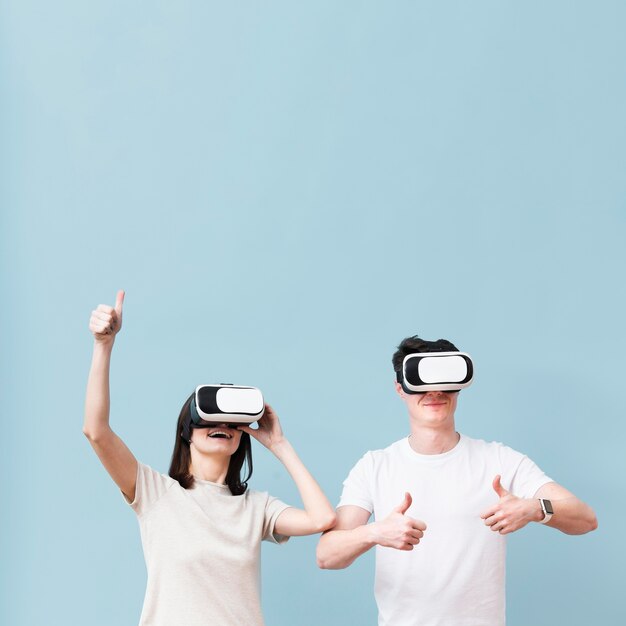 Vista frontal de la pareja divirtiéndose con casco de realidad virtual
