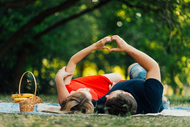 Vista frontal pareja haciendo una forma de corazón en el aire