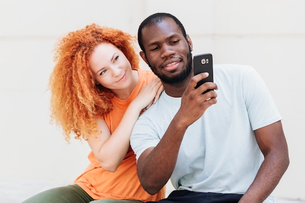 Foto gratuita vista frontal de la pareja interracial revisando el teléfono
