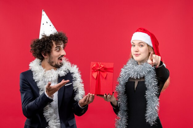 Vista frontal pareja joven celebración de año nuevo presente en la pared roja emoción amor de navidad