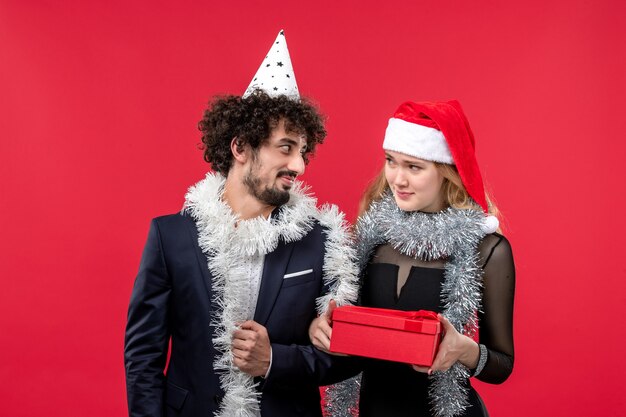 Vista frontal pareja joven con regalo de año nuevo en la pared roja fiesta color amor de navidad