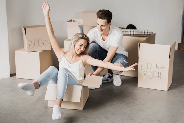 Vista frontal pareja jugando con cajas de cartón