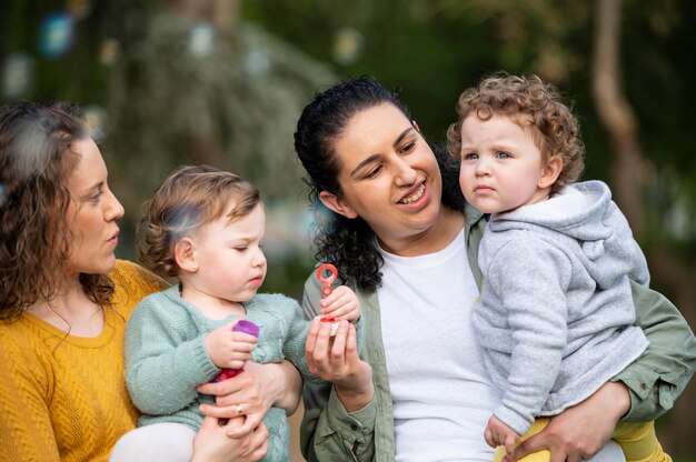 Vista frontal de la pareja lgbt al aire libre con niños