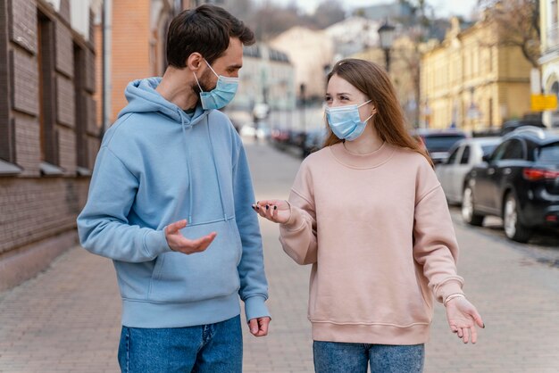 Vista frontal de la pareja con máscara médica en la ciudad