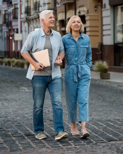 Vista frontal de la pareja senior con tableta dando un paseo por la ciudad