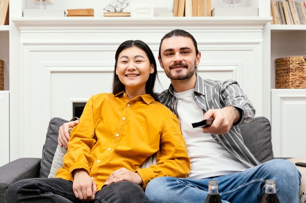 Vista frontal de la pareja sentada en el sofá viendo la televisión