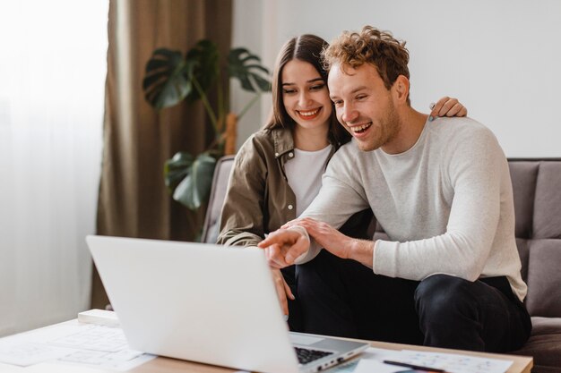 Vista frontal de la pareja sonriente haciendo planes para remodelar la casa juntos