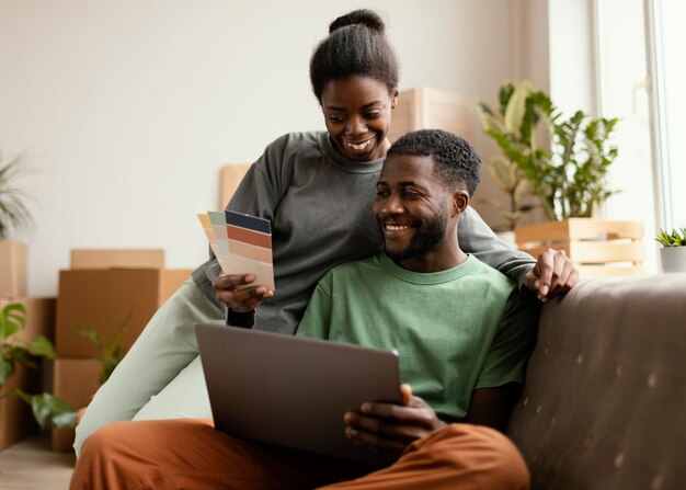 Vista frontal de la pareja sonriente en el sofá haciendo planes para redecorar la casa