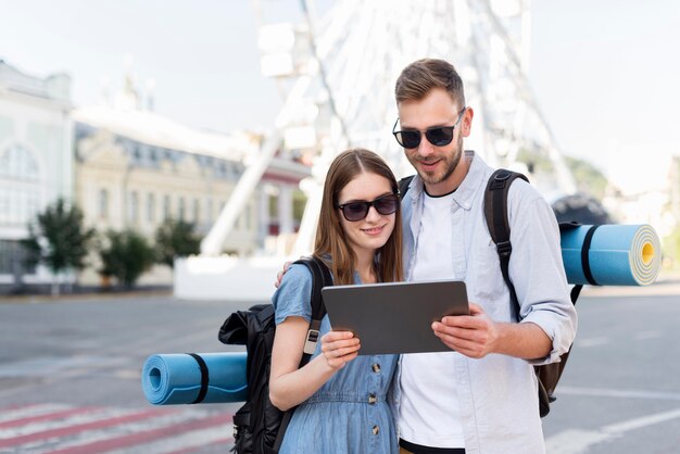 Vista frontal de la pareja de turistas mirando tablet