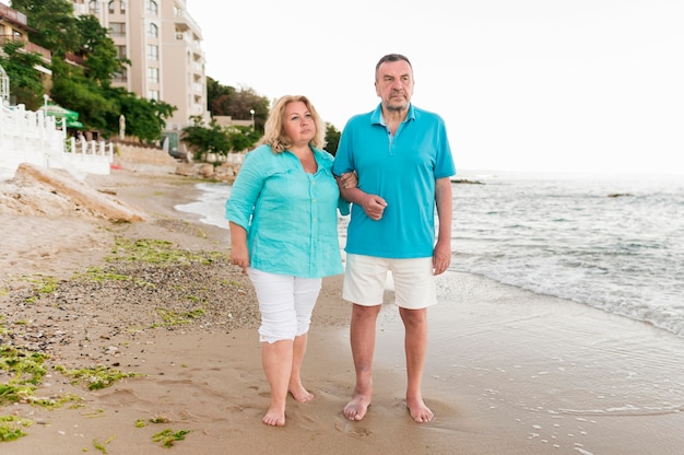 Vista frontal de la pareja de turistas senior en la playa