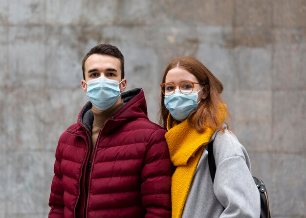 Vista frontal de la pareja vistiendo máscaras médicas juntos