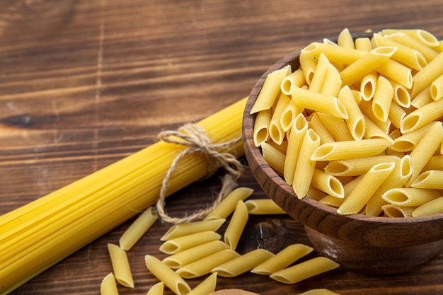 Vista frontal de la pasta cruda de forma larga y poco en la superficie marrón