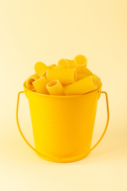 Una vista frontal de pasta dentro de la cesta formada cruda dentro de la cesta amarilla sobre el fondo crema comida comida italiana espagueti