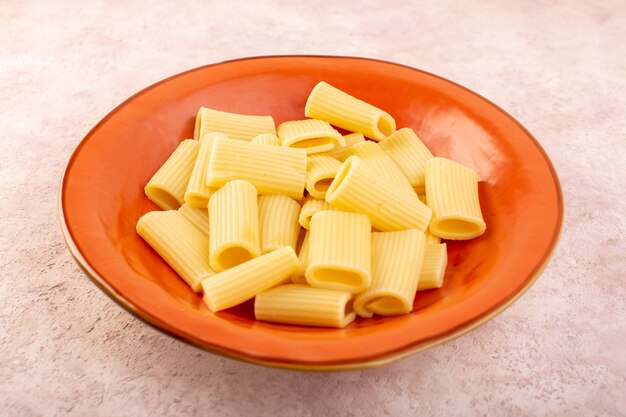 Una vista frontal de la pasta italiana cocida sabrosa y salada dentro de la placa redonda naranja en el escritorio rosa