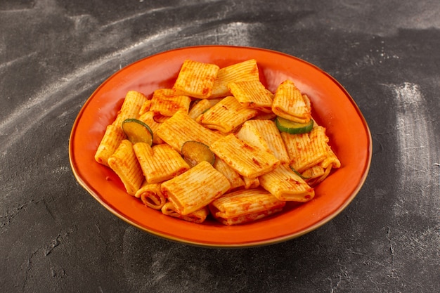 Foto gratuita una vista frontal de pasta italiana cocida con salsa de tomate y pepino dentro de la placa sobre la superficie oscura