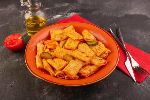 Foto gratuita una vista frontal de pasta italiana cocida con salsa de tomate y pepino dentro de la placa sobre la superficie oscura