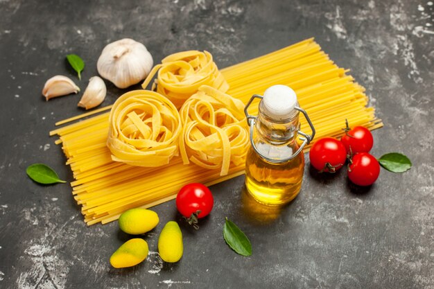 Vista frontal de pasta italiana cruda con ajo y tomates en comida de color gris claro cocina comida