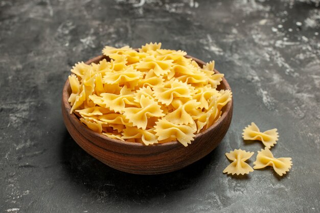 Vista frontal de la pasta italiana cruda dentro de la placa en color gris oscuro masa de comida fotográfica muchos alimentos