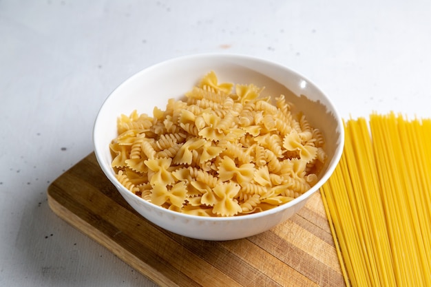 Una vista frontal de pasta italiana cruda formada poco y larga formada en la mesa de madera pasta comida italiana