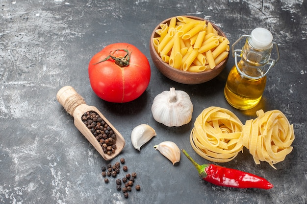 Vista frontal de pasta italiana cruda con huevos, tomate y aceite sobre fondo gris claro, masa, comida, comida, cocina