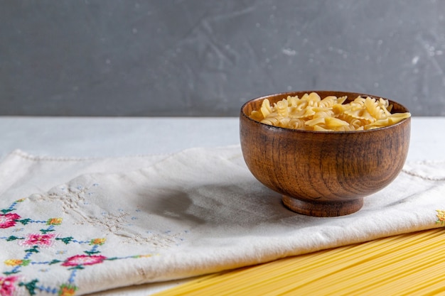 Foto gratuita una vista frontal de pasta italiana cruda largo y pequeño tazón de pasta