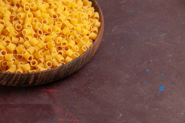 Foto gratuita vista frontal de la pasta italiana cruda poco formada dentro de la placa en el escritorio oscuro