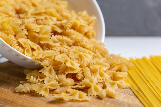 Una vista frontal de pasta italiana cruda poco formada en la mesa de madera pasta comida italiana