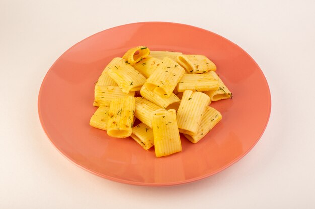 Una vista frontal de pasta italiana con hierbas verdes secas dentro de la placa rosa sobre blanco