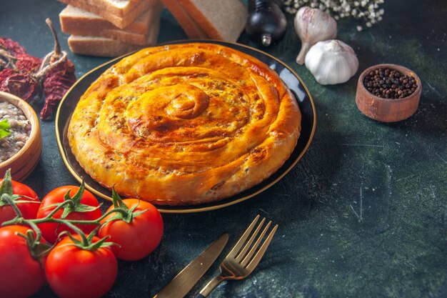 Vista frontal del pastel de carne dentro de la sartén con tomates sobre fondo azul oscuro pastel de alimentos pastelería hornear masa de galletas pastel de horno