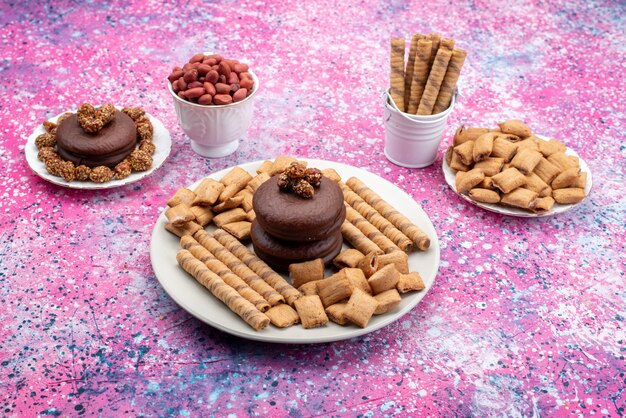 Vista frontal del pastel de chocolate con galletas y papas fritas en la superficie colorida