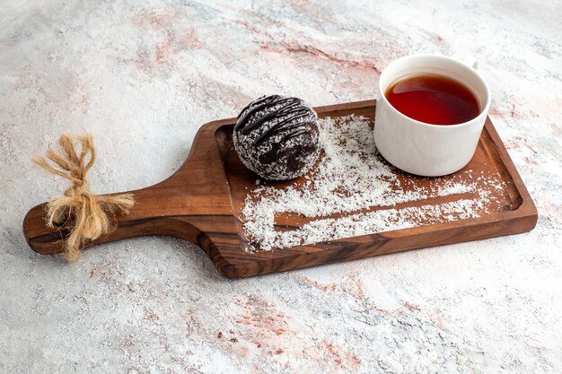 Vista frontal de pastel de chocolate con una taza de té en el escritorio blanco pastel de chocolate galleta galletas dulces de azúcar