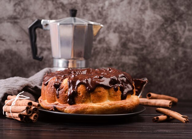 Vista frontal del pastel con cobertura de chocolate y palitos de canela