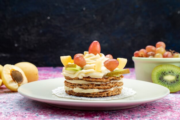 Vista frontal de pastel de crema con frutas frescas en rodajas en la superficie oscura