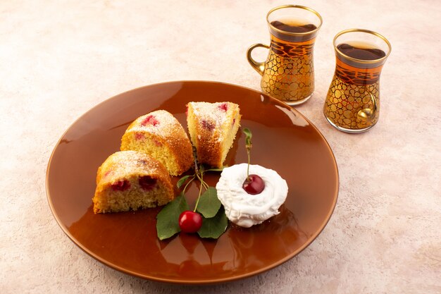 Una vista frontal pastel de frutas al horno delicioso en rodajas con cerezas rojas en el interior y azúcar en polvo dentro de la placa redonda marrón en rosa