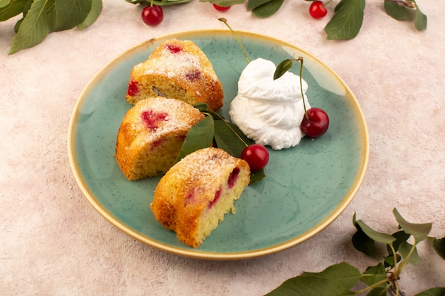 Una vista frontal pastel de frutas horneado delicioso en rodajas con cerezas rojas en el interior y azúcar en polvo dentro de la placa redonda verde en rosa